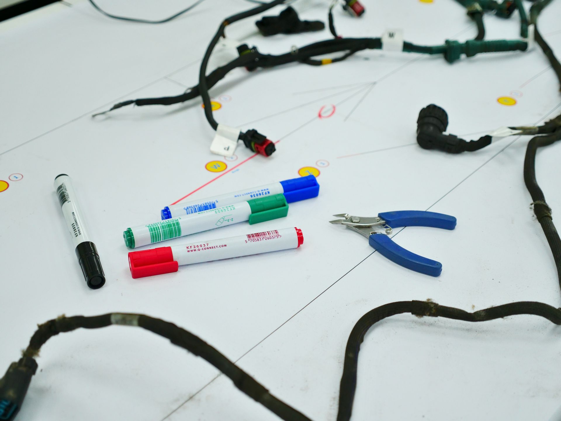 Engineering blueprints lying on the workbench alongside pens and tools for reverse engineering a product
