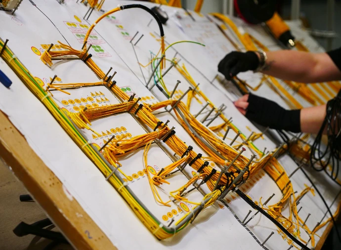 Yellow wiring harness on a wire harness board, being manufactured by hand