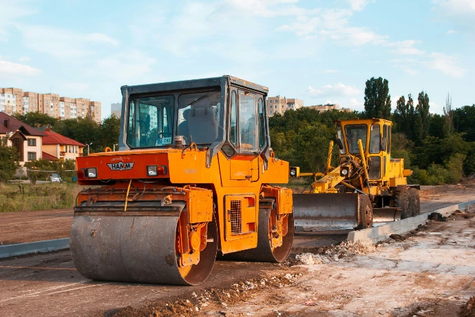Steam roller and digger on an urban construction site