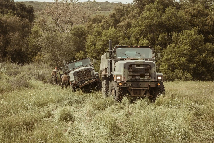 Military vehicles driving through a grassy field