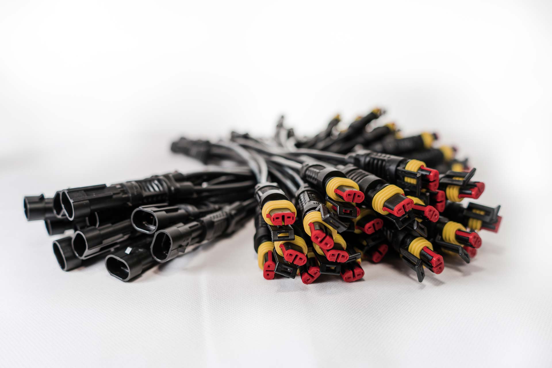Two piles of overmoulded cables with different connectors on each end