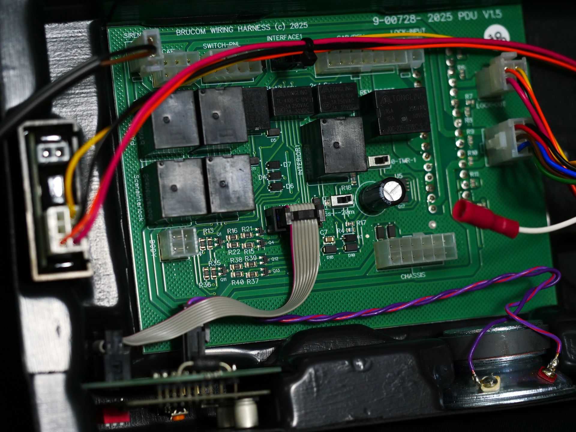 A PCB connected with wires to a speaker system inside a black plastic casing